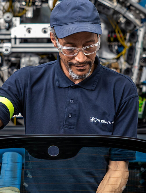 Man working on assembly line assessing automotive glass